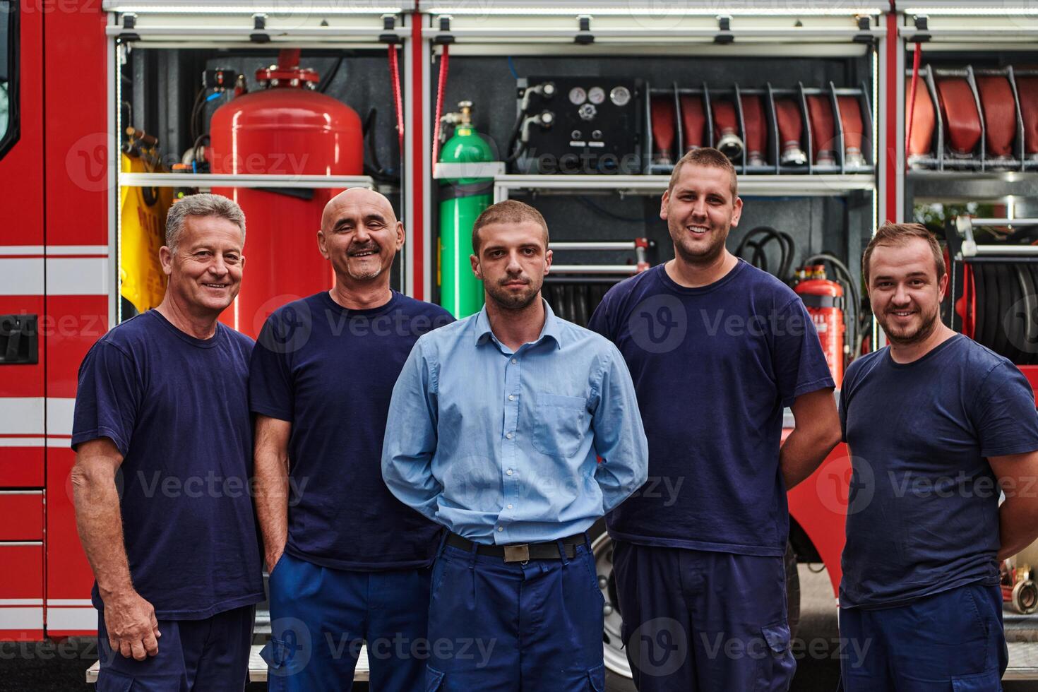 A skilled and dedicated professional firefighting team proudly poses in front of their state of the art firetruck, showcasing their modern equipment and commitment to ensuring public safety. photo