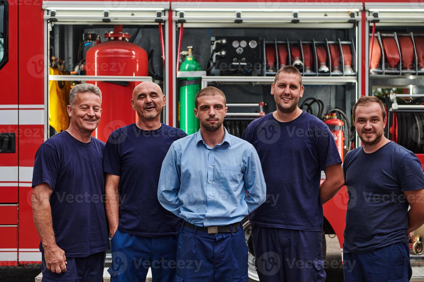 A skilled and dedicated professional firefighting team proudly poses in front of their state of the art firetruck, showcasing their modern equipment and commitment to ensuring public safety. photo