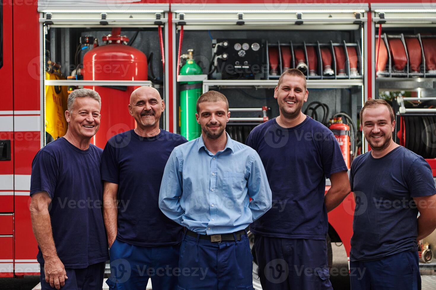 A skilled and dedicated professional firefighting team proudly poses in front of their state of the art firetruck, showcasing their modern equipment and commitment to ensuring public safety. photo