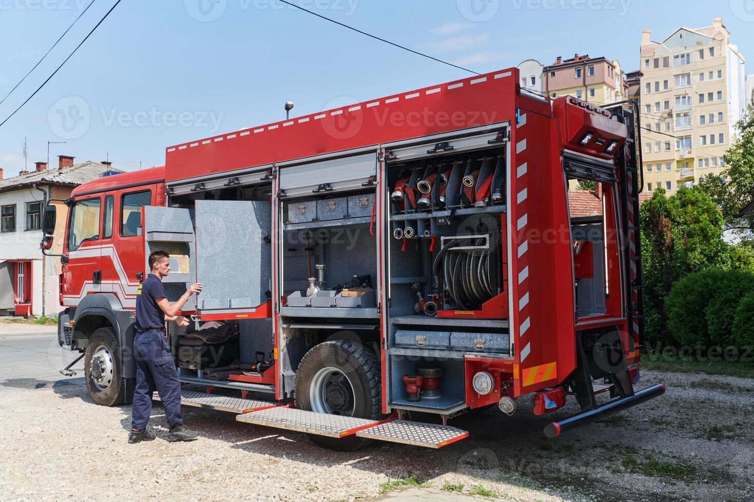A dedicated firefighter preparing a modern firetruck for deployment to hazardous fire-stricken areas, demonstrating readiness and commitment to emergency response photo