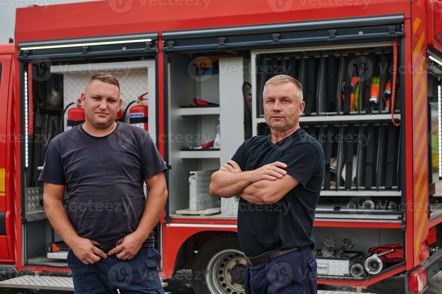 A skilled and dedicated professional firefighting team proudly poses in front of their state of the art firetruck, showcasing their modern equipment and commitment to ensuring public safety. photo