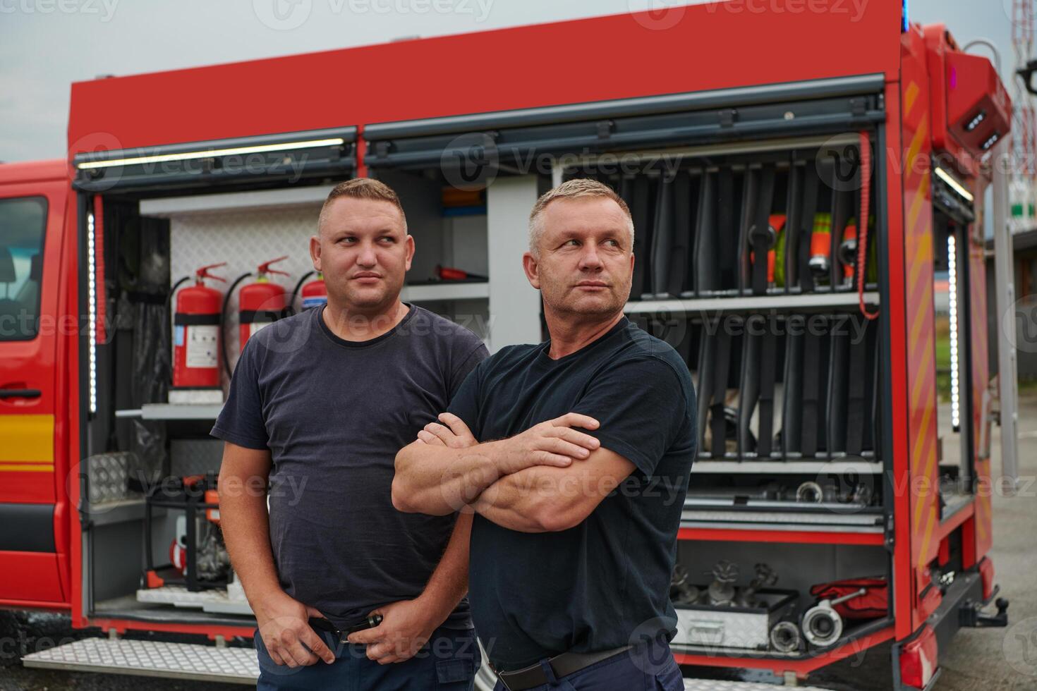 A skilled and dedicated professional firefighting team proudly poses in front of their state of the art firetruck, showcasing their modern equipment and commitment to ensuring public safety. photo