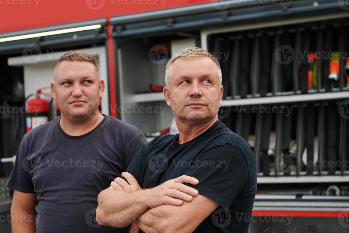 A skilled and dedicated professional firefighting team proudly poses in front of their state of the art firetruck, showcasing their modern equipment and commitment to ensuring public safety. photo