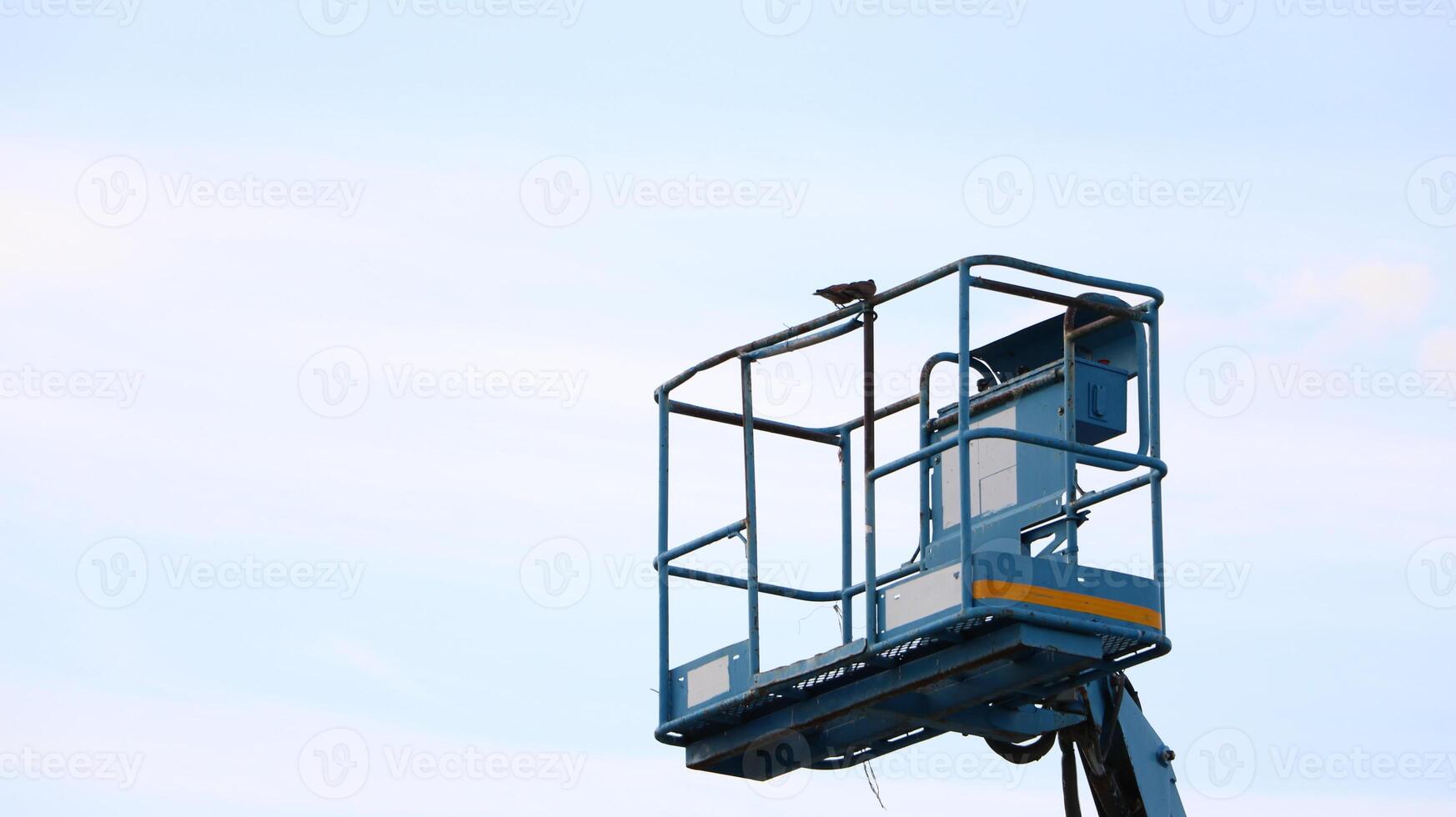 The aerial platform of the boom lift is carried to heights. with a bird perched on top photo