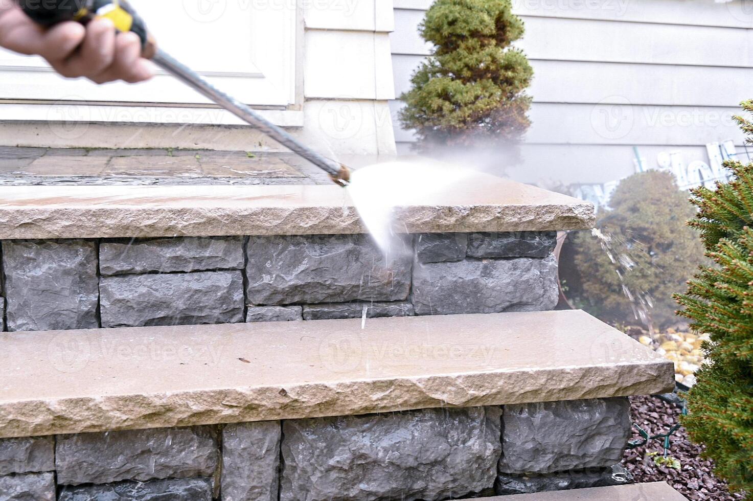 Close up of high pressure water jet during cleaning outdoor porch stairs. photo