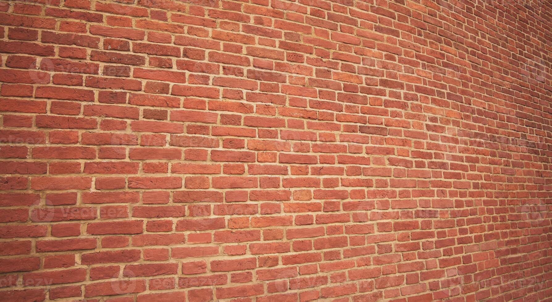 The wall is made of dark red brick. The texture of the dark brown and red brick wall creates a panoramic background. photo