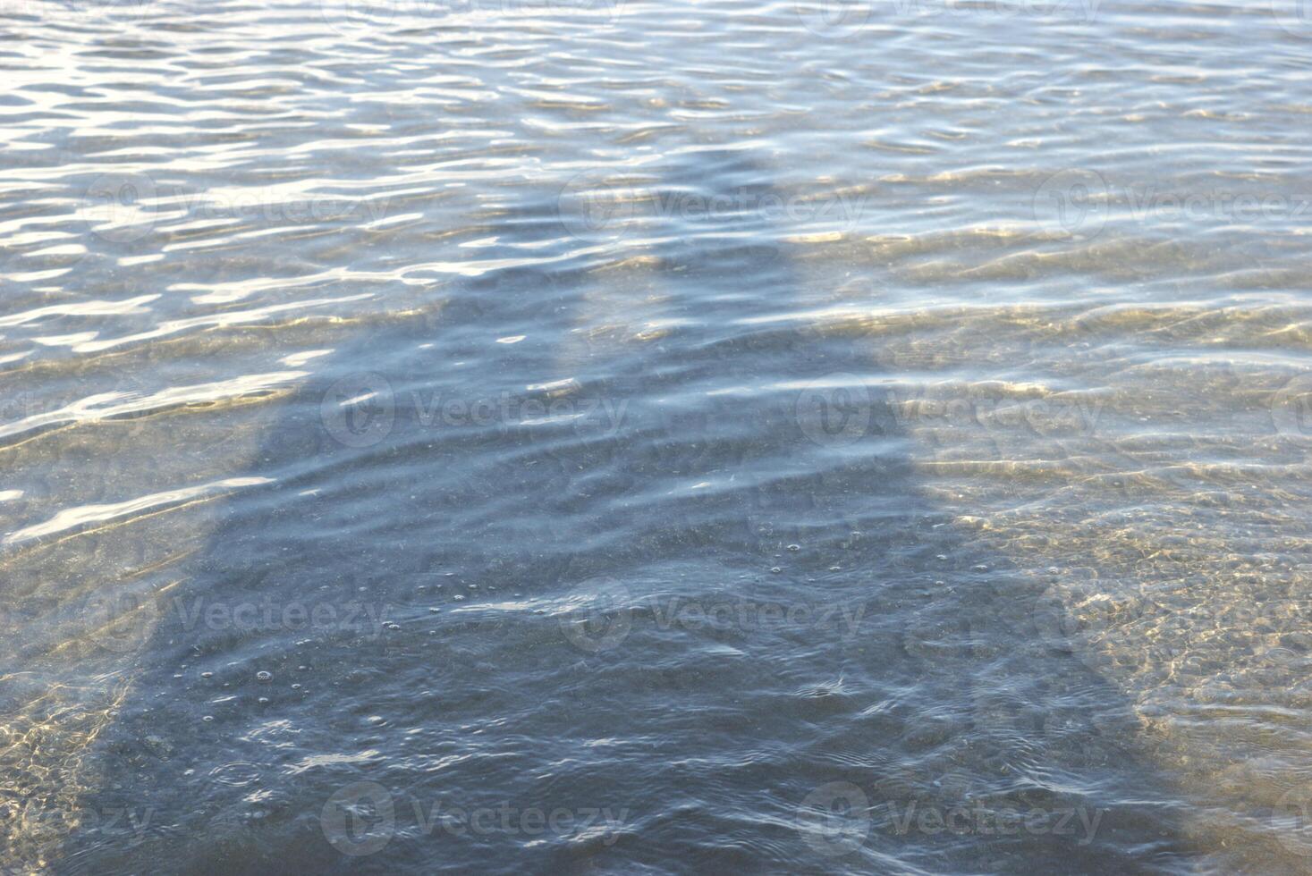 Shadow of a couple on a beach with water ripples in a sunny summer day photo