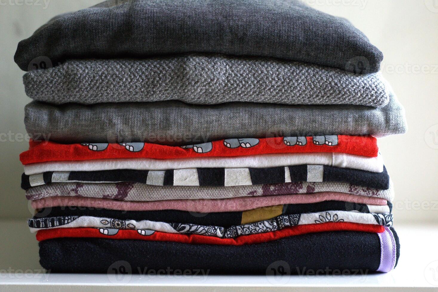 Stack of folded clothes on the table, laundry and chores concept photo