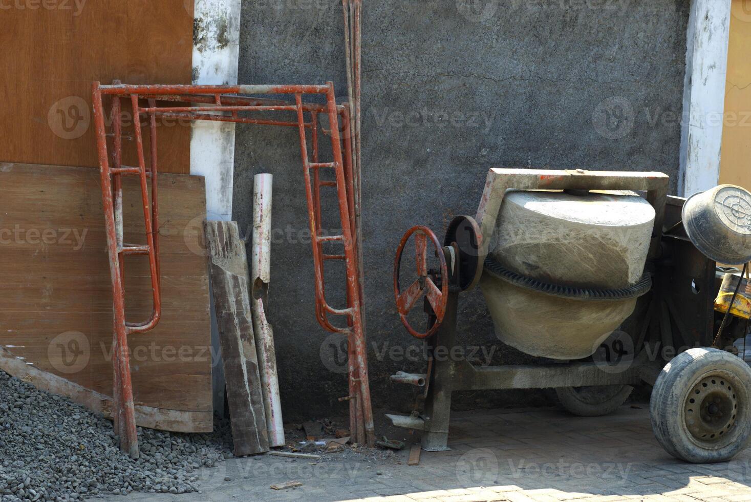 Cement mixer in a construction site with some construction material, concrete maker machine photo