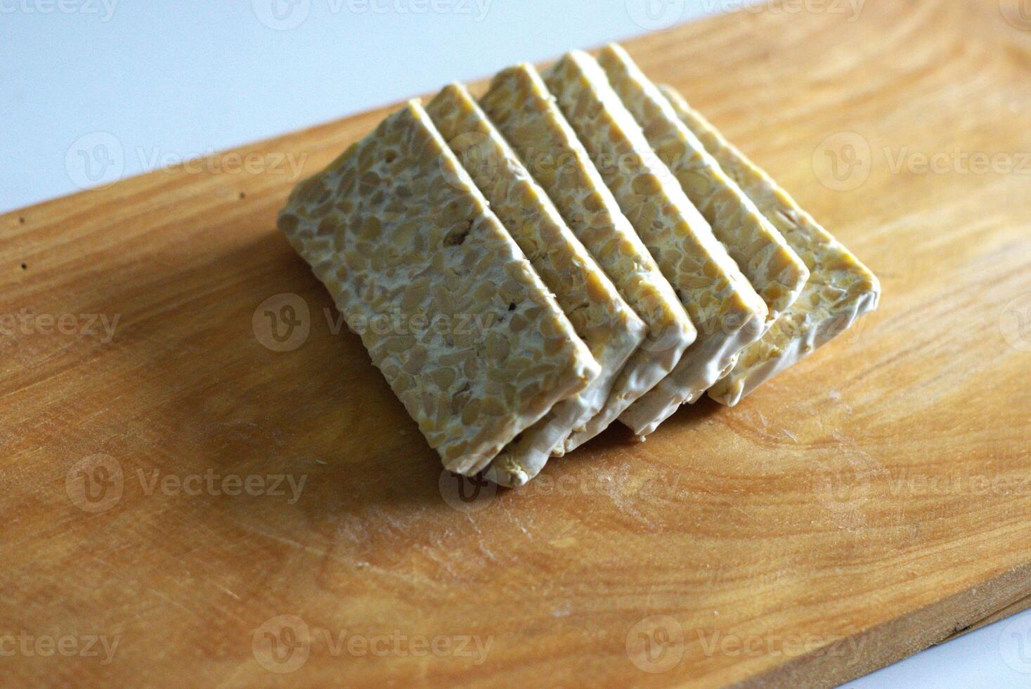 Slices of Raw Tempe or tempeh on a wooden cutting board, traditional Indonesian food made of fermented soybean photo