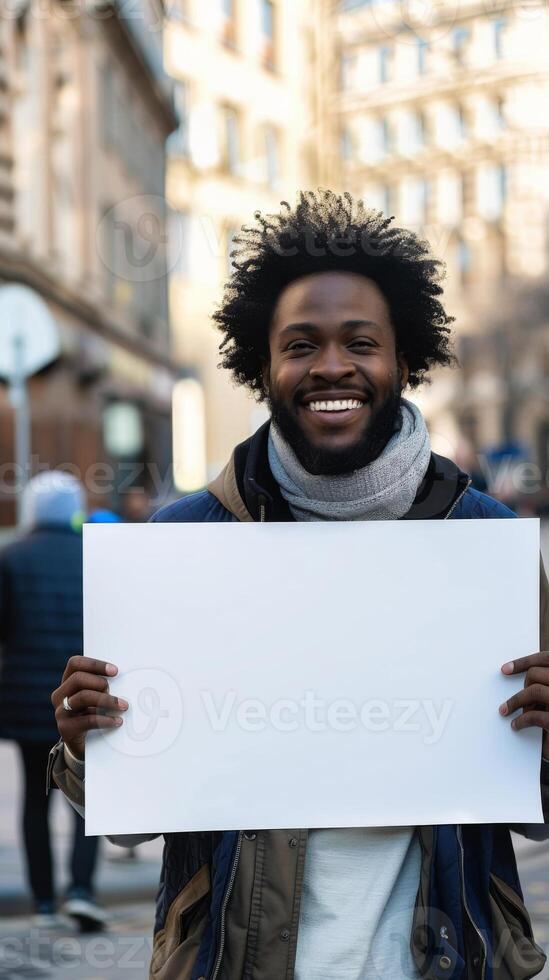 A smiling Black man with an afro and beard holds a blank white sign photo