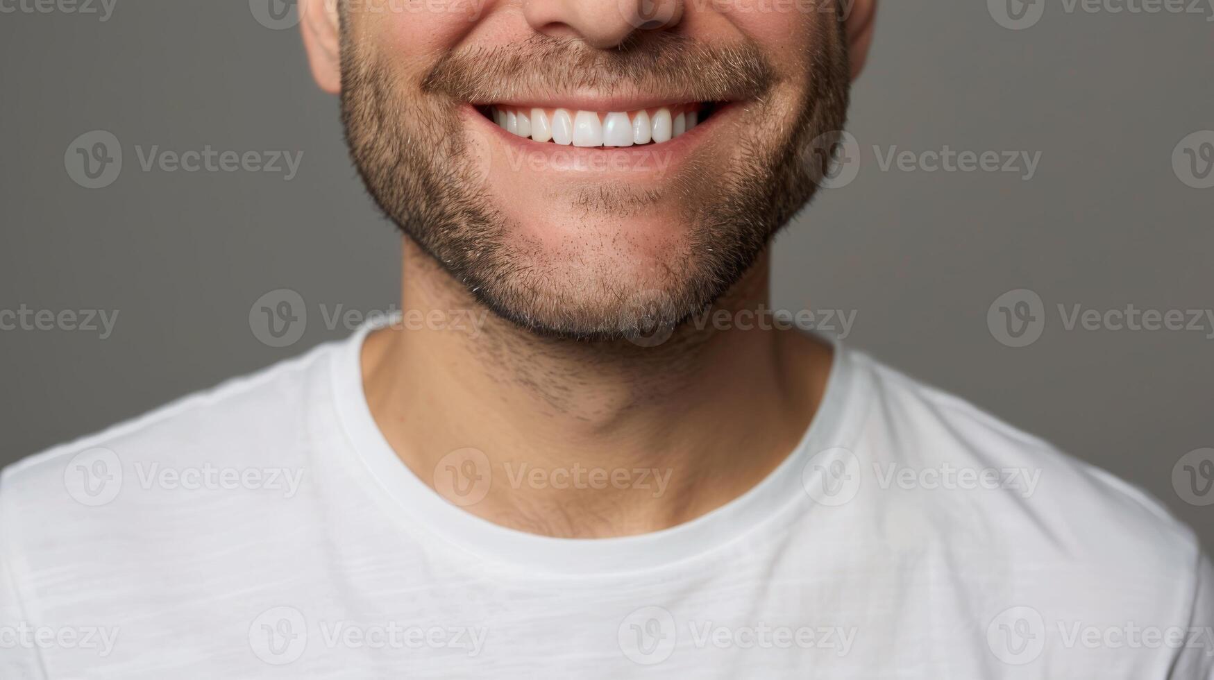 Close-up of a mans smiling mouth with white teeth against a gray background photo