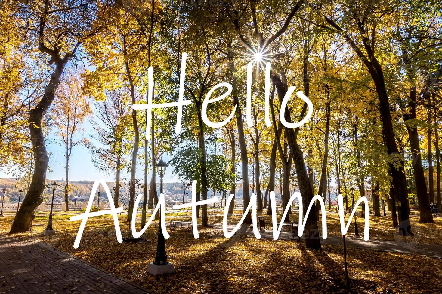 The words Hello Autumn on the background of autumn park lit by sun in golden autumn season. Greeting card. The concept of the beginning of autumn. photo