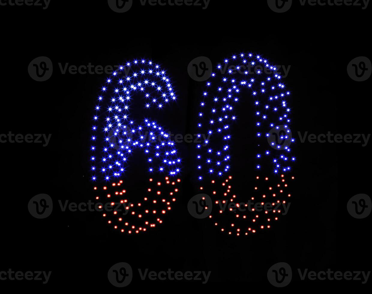 Drone light shows on black night sky background. A figure of the number sixty, six, zerro, 60 made of glowing drones. photo