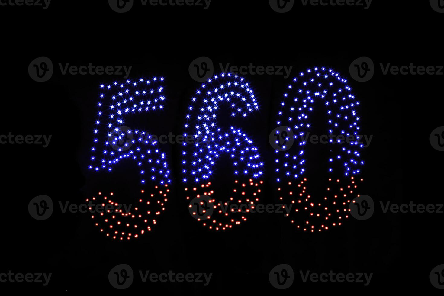Drone light shows on black night sky background. A figure of the number five hundred and sixty, six, five, zerro, 560 made of glowing drones. photo