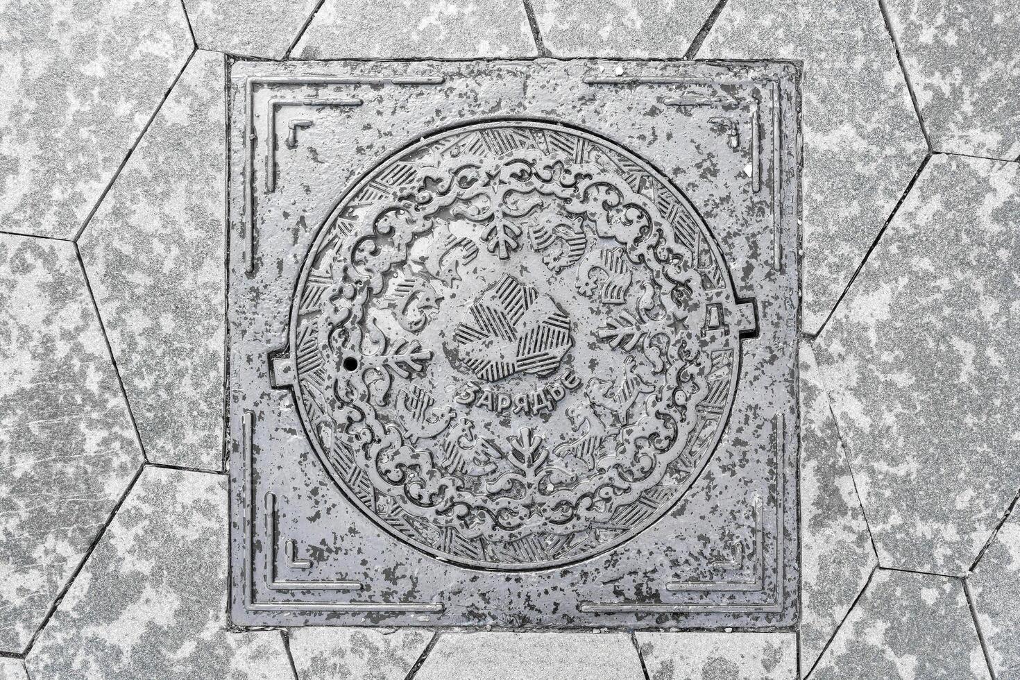 The cover of a sewer manhole on the pavement, with the inscription Zaryadye in Russian. photo