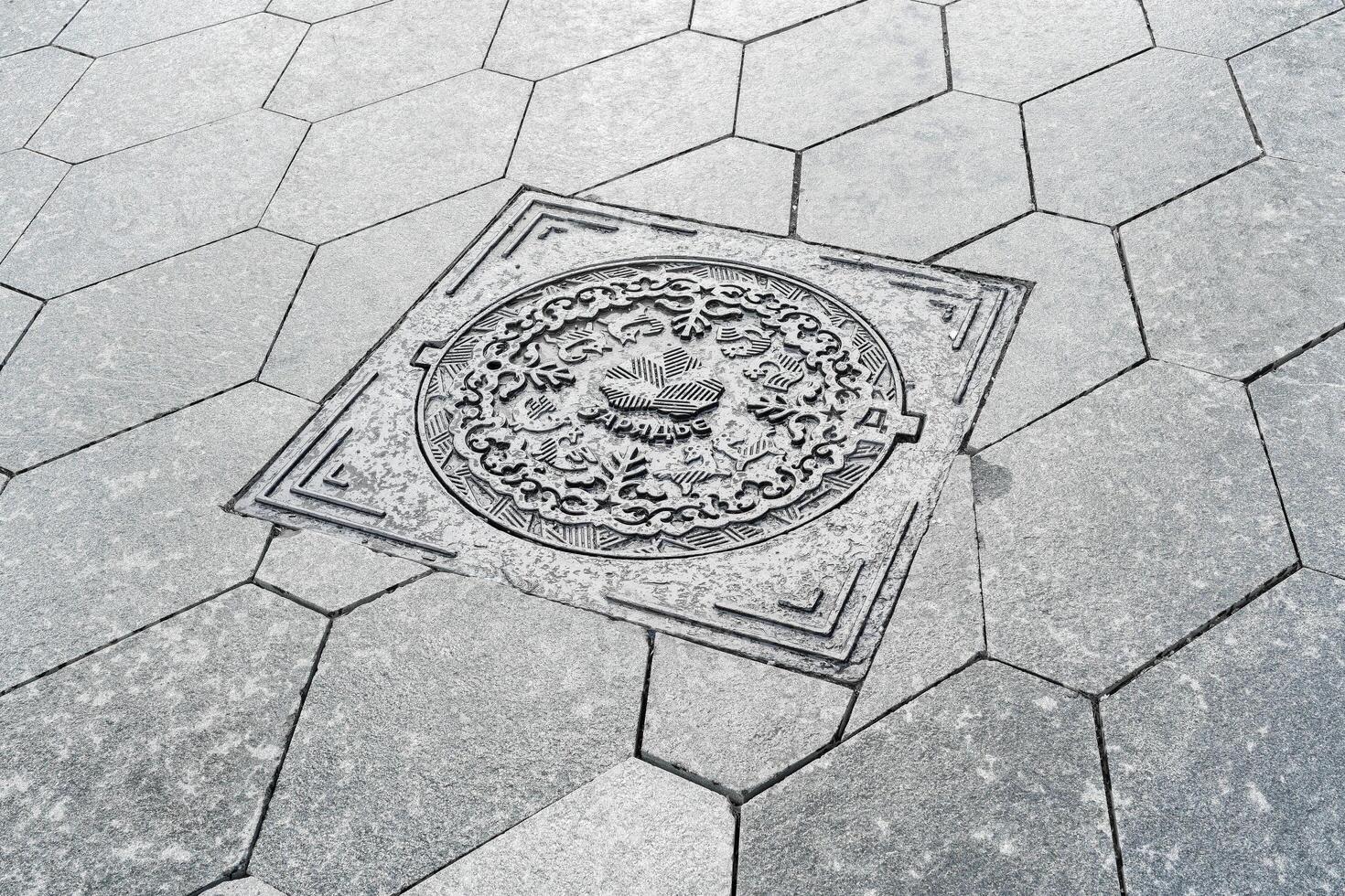 The cover of a sewer manhole on the pavement, with the inscription Zaryadye in Russian. photo