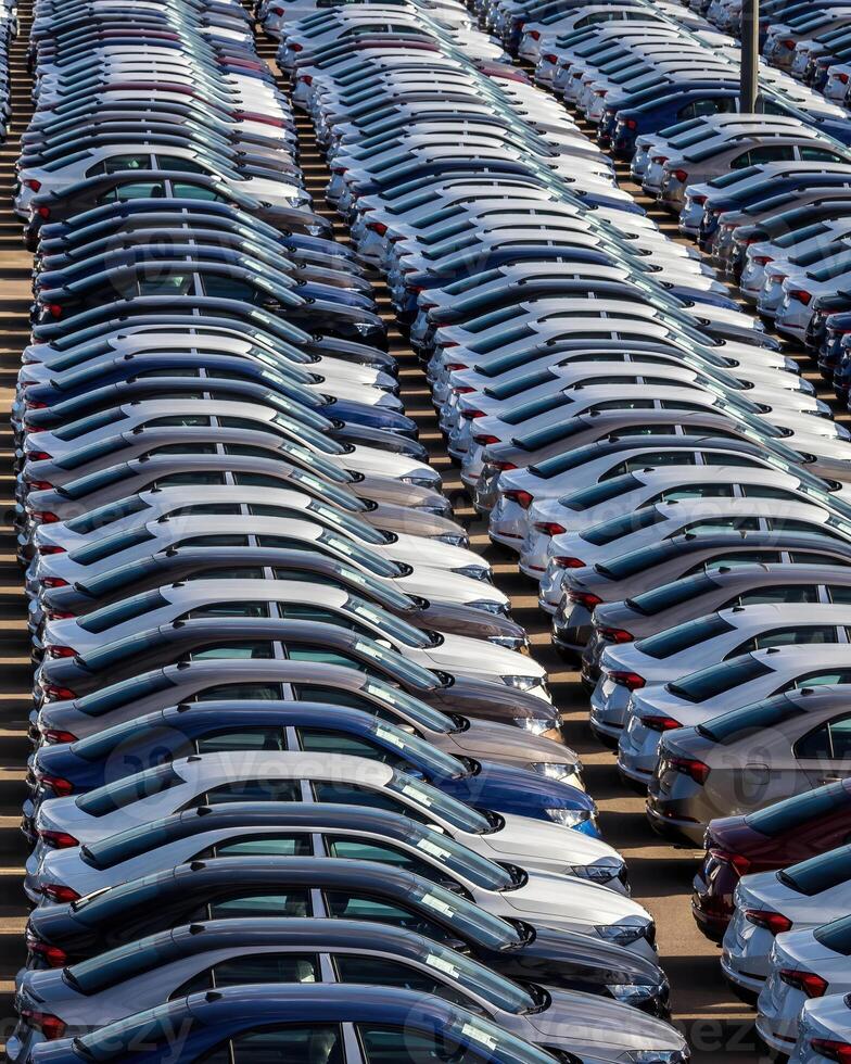 Rows of a new cars parked in a distribution center on a car factory on a sunny day. photo
