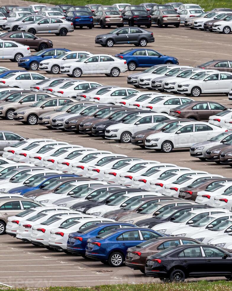 Rows of a new cars parked in a distribution center of a car factory. photo