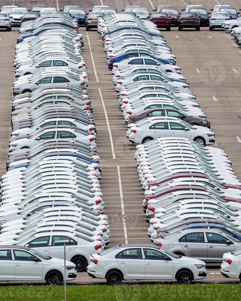 Rows of a new cars parked in a distribution center of a car factory. photo