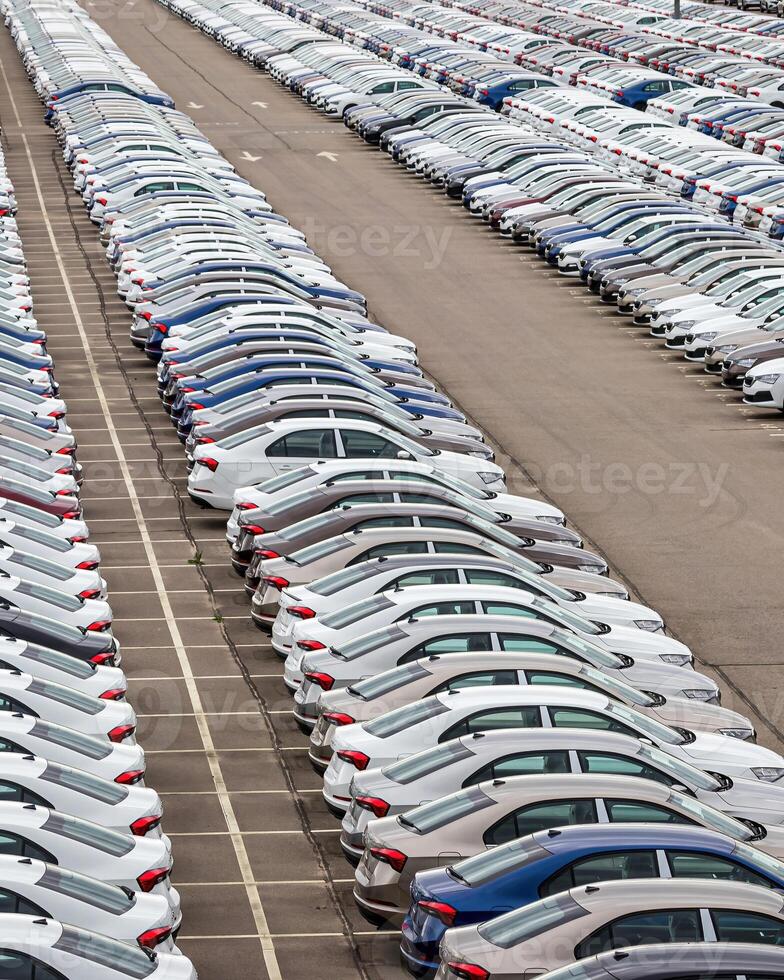 Rows of a new cars parked in a distribution center of a car factory. photo