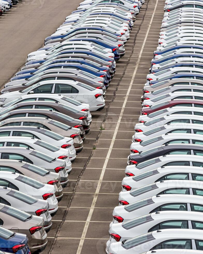 Rows of a new cars parked in a distribution center of a car factory. photo