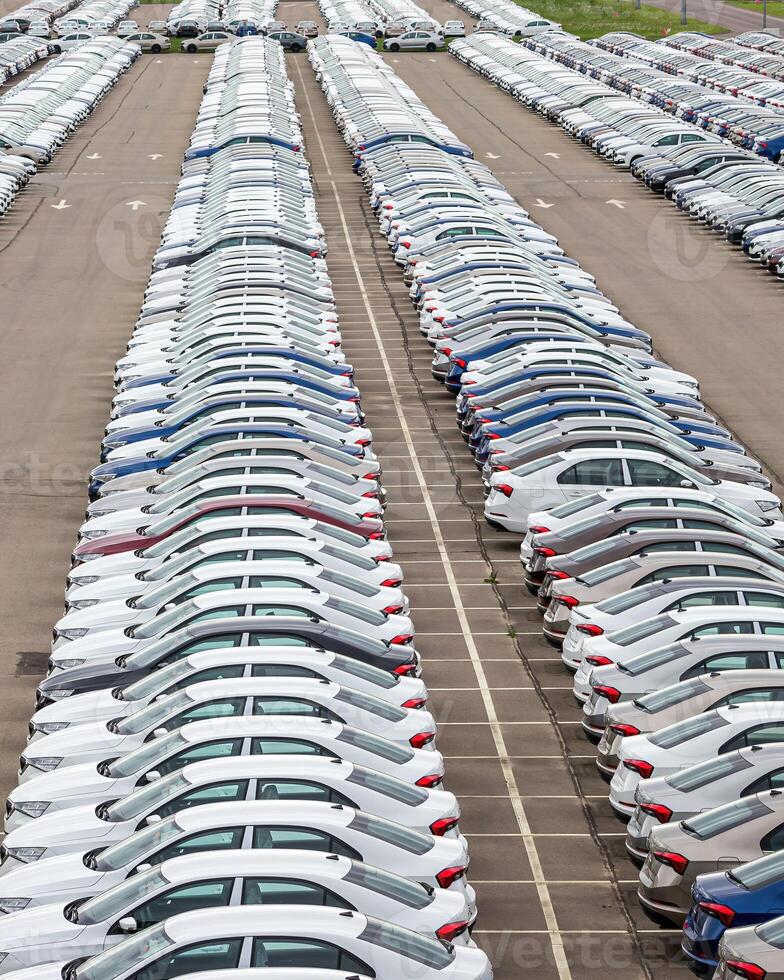 Rows of a new cars parked in a distribution center of a car factory. photo