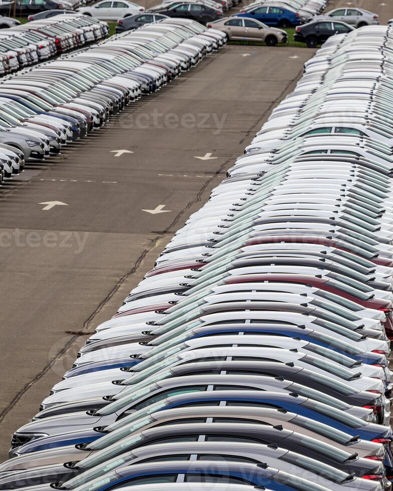 Rows of a new cars parked in a distribution center of a car factory. photo