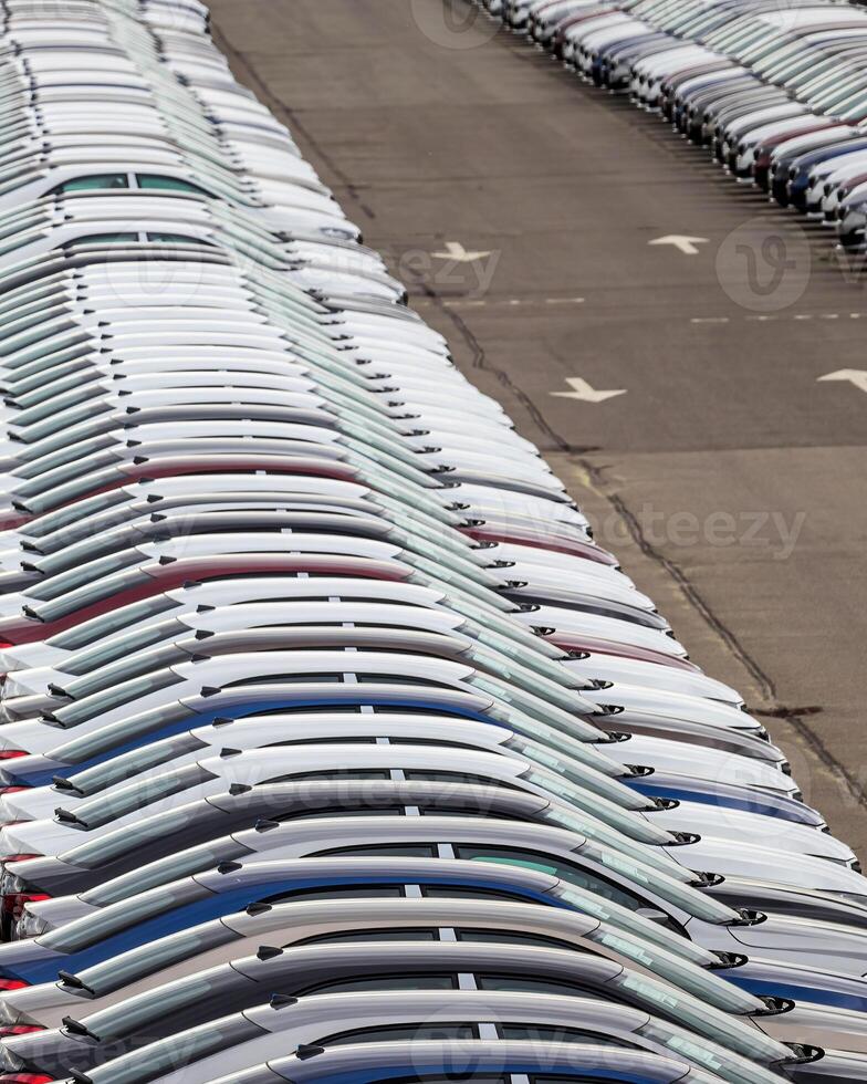 Rows of a new cars parked in a distribution center of a car factory. photo