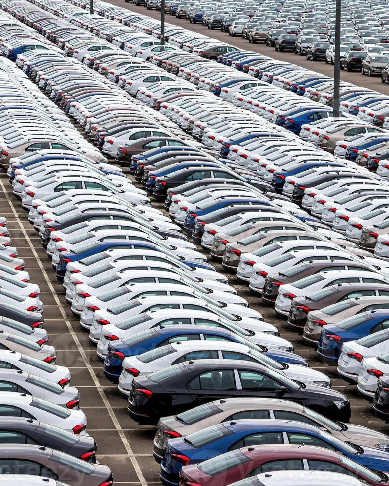 Rows of a new cars parked in a distribution center of a car factory. photo