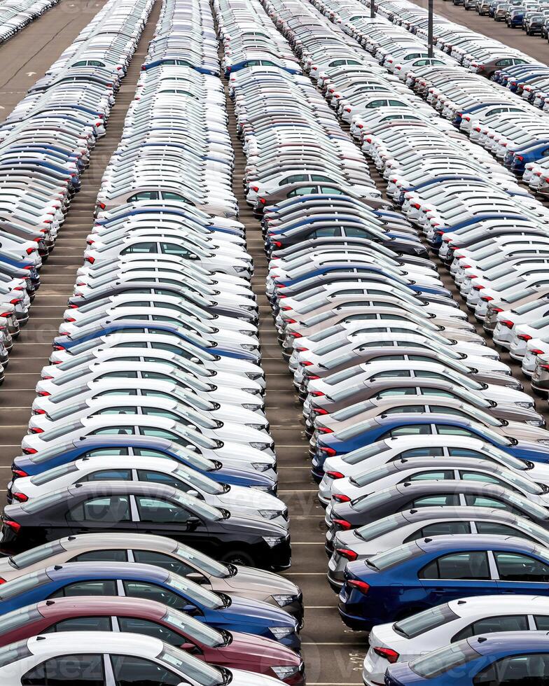 Rows of a new cars parked in a distribution center of a car factory. photo