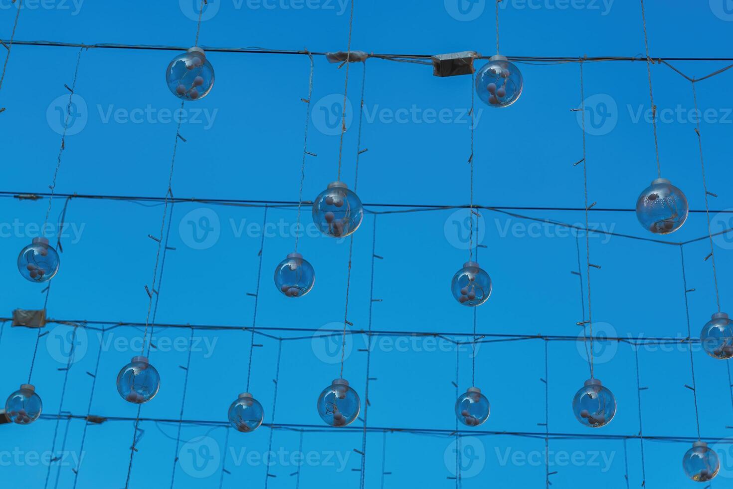 Festive hanging garlands with light bulbs against the background of a blue sky. photo