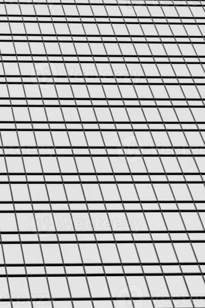 Fragment of a modern office building. Abstract geometric background. Part of a skyscraper with glass windows. Black and white. photo