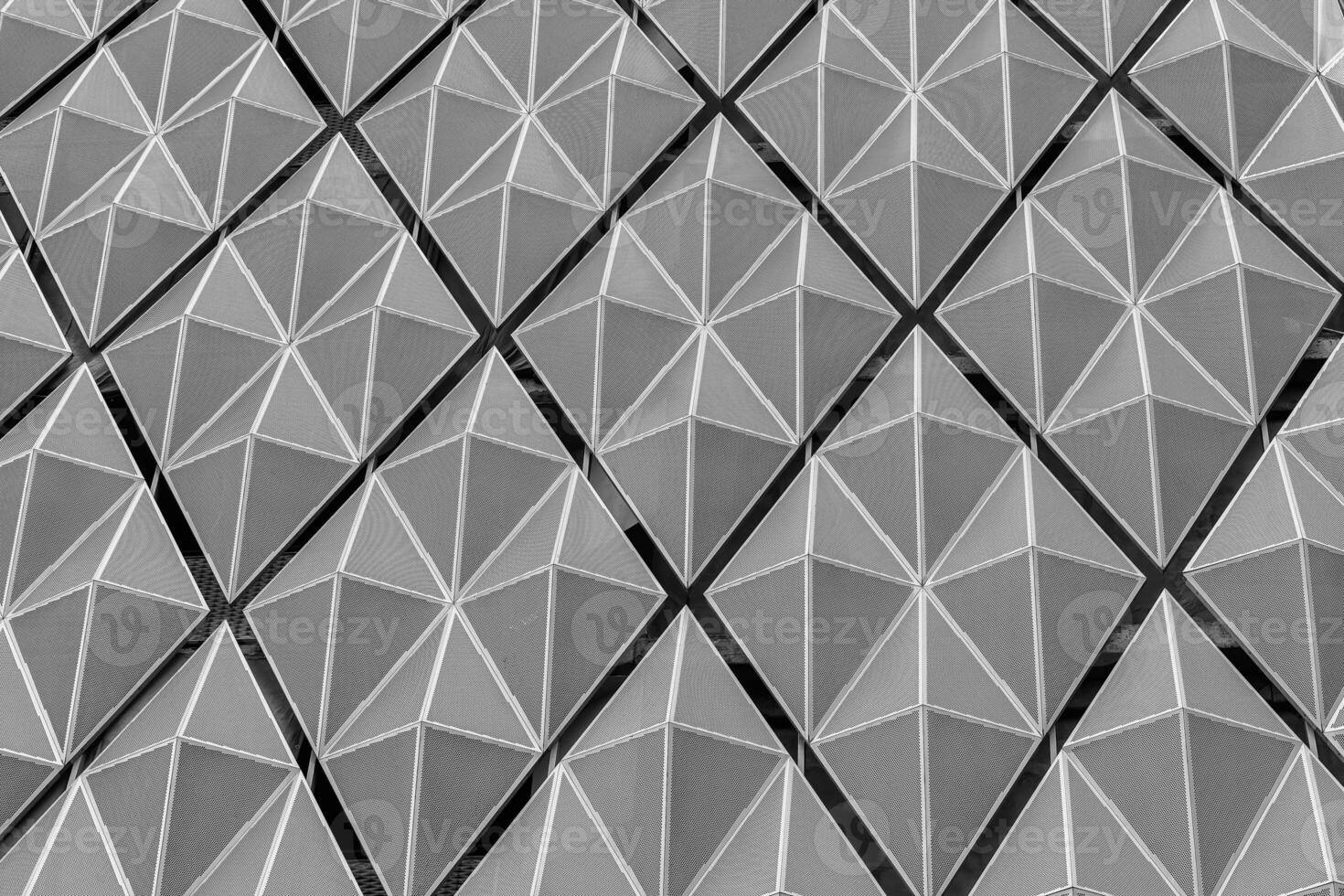 Fragment of a modern building. Abstract geometric background. Part of the facade of a skyscraper with metal diamond-shaped grids. photo