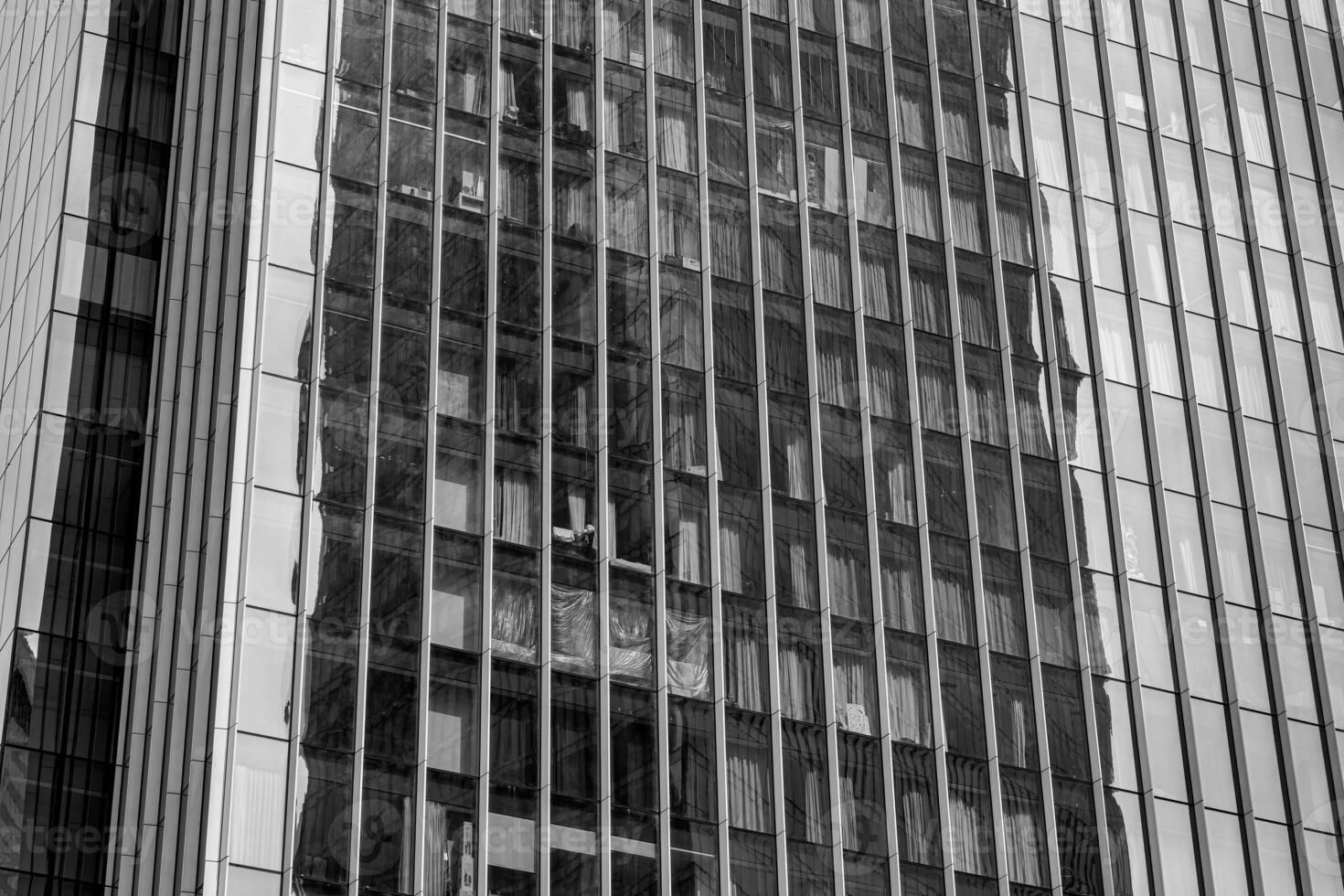 Fragment of a modern office building. Abstract geometric background. Part of a skyscraper with glass windows. Black and white. photo