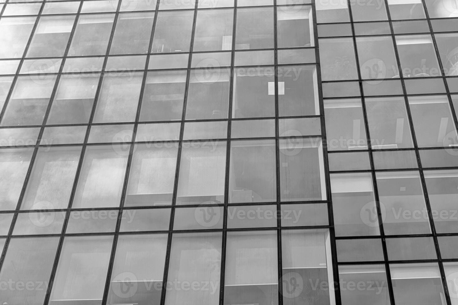 Fragment of a modern office building. Abstract geometric background. Part of a skyscraper with glass windows. Black and white. photo
