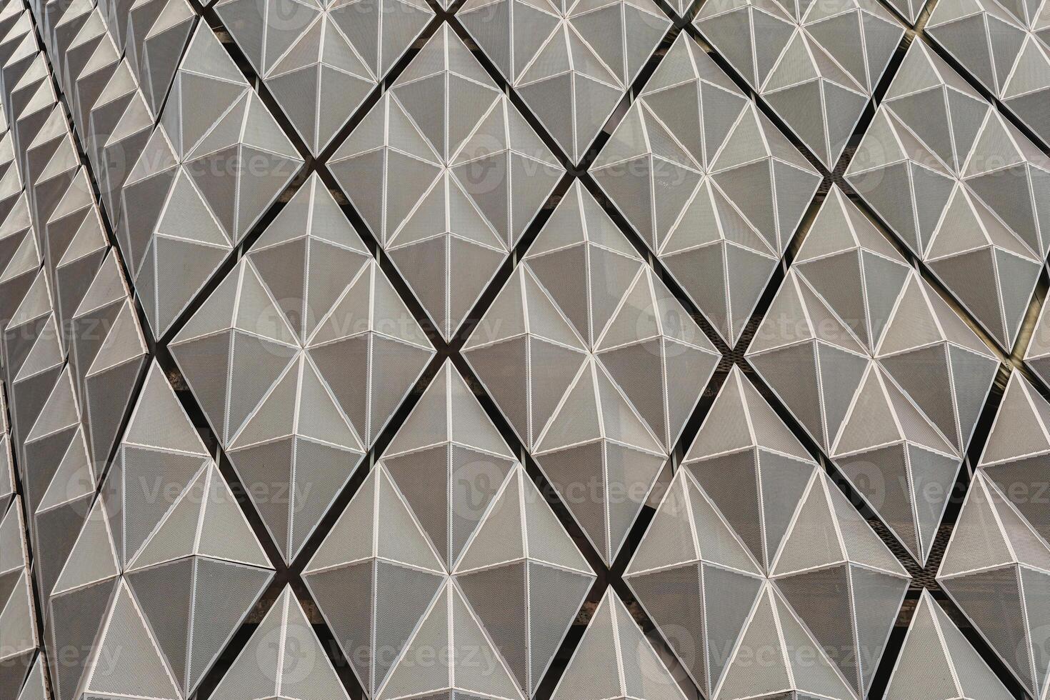 Fragment of a modern building. Abstract geometric background. Part of the facade of a skyscraper with metal diamond-shaped grids. photo