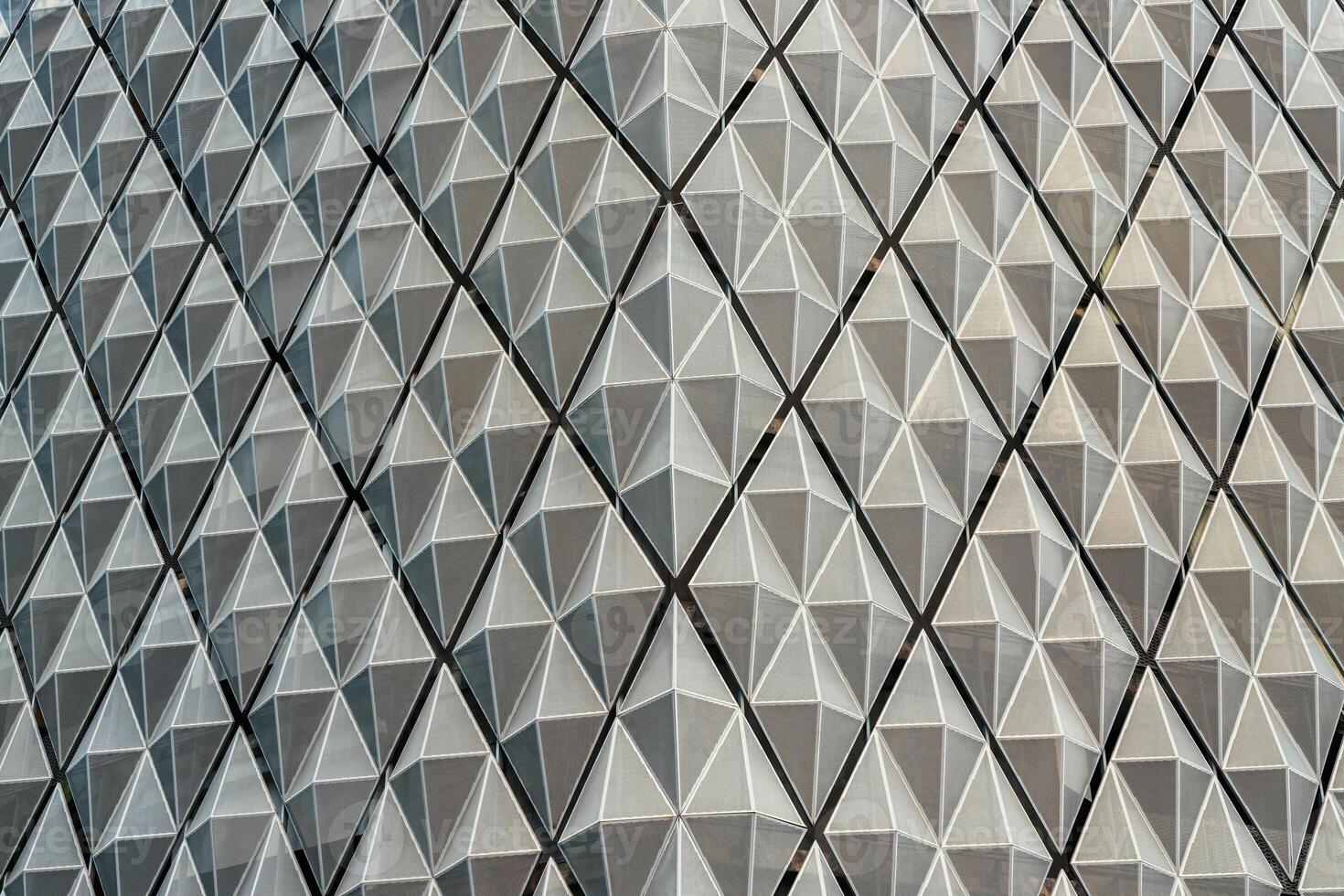 Fragment of a modern building. Abstract geometric background. Part of the facade of a skyscraper with metal diamond-shaped grids. photo