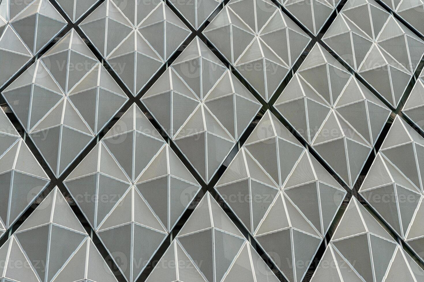 Fragment of a modern building. Abstract geometric background. Part of the facade of a skyscraper with metal diamond-shaped grids. photo