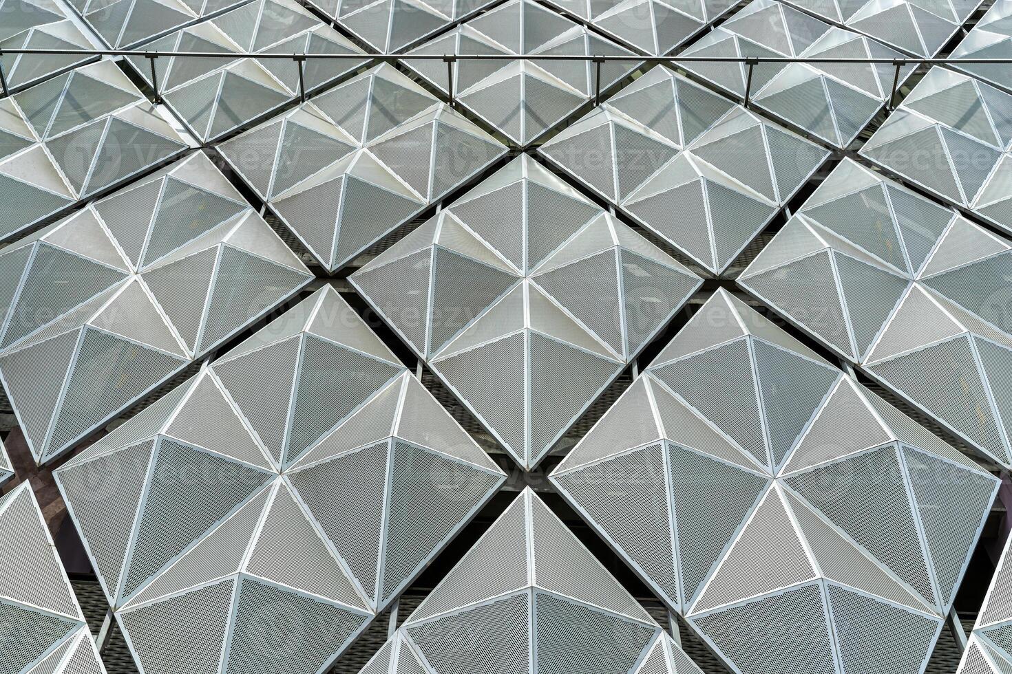 Fragment of a modern building. Abstract geometric background. Part of the facade of a skyscraper with metal diamond-shaped grids. photo