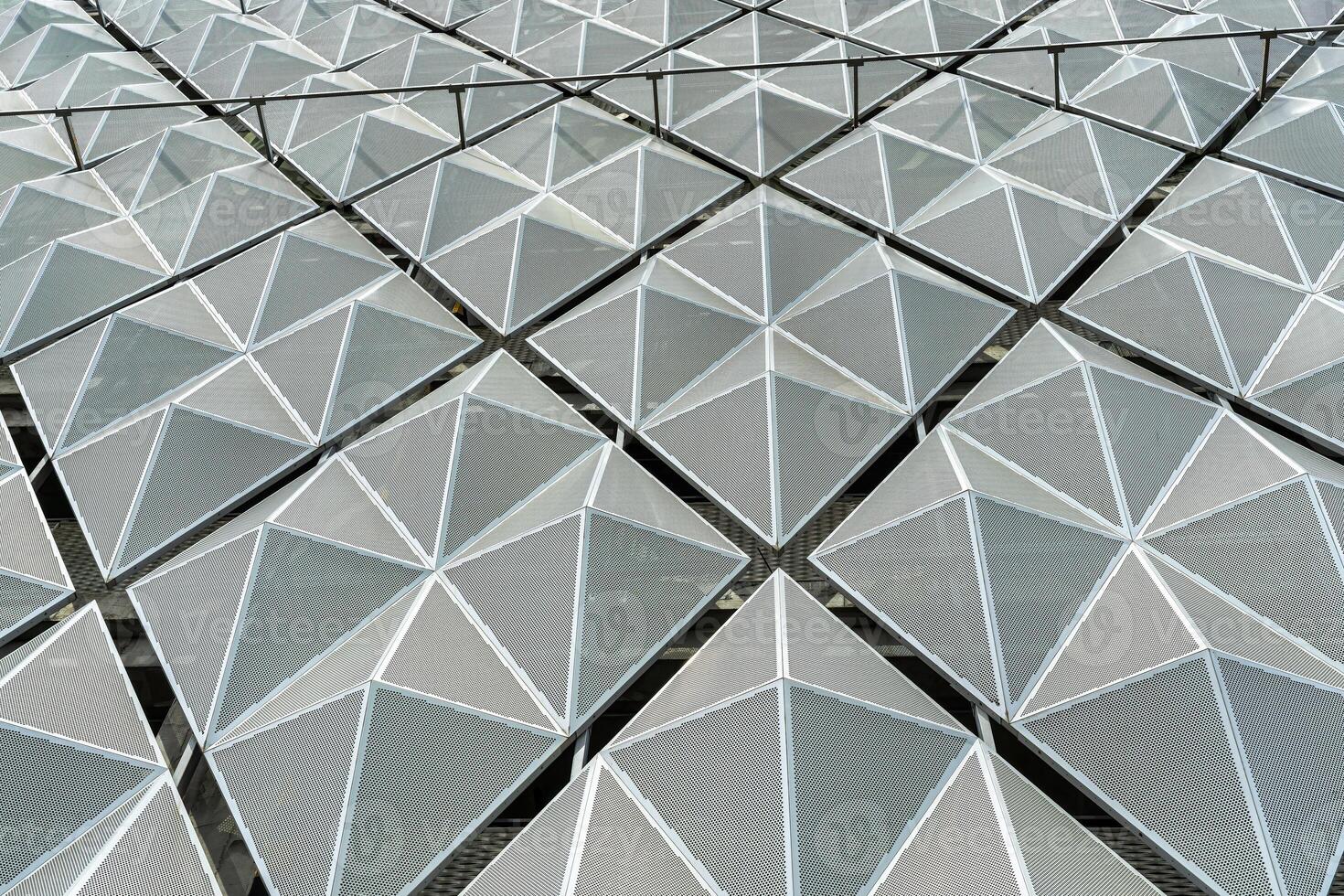 Fragment of a modern building. Abstract geometric background. Part of the facade of a skyscraper with metal diamond-shaped grids. photo