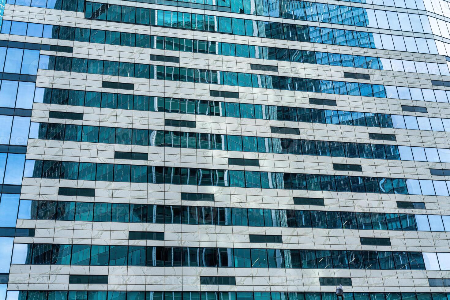 Fragment of a modern office building. Abstract geometric background. Part of a skyscraper with glass windows. photo