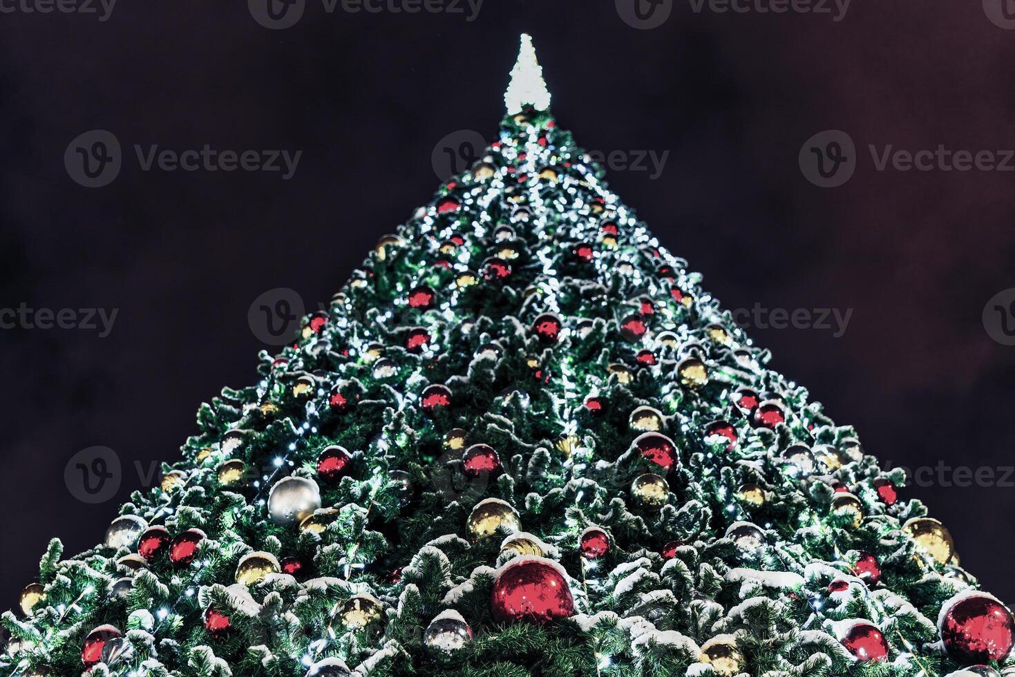 Artificial Christmas tree in garlands at night. photo