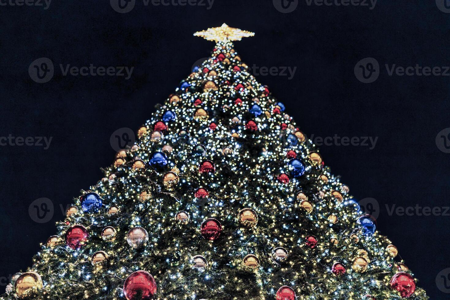 Artificial Christmas tree in garlands at night. photo