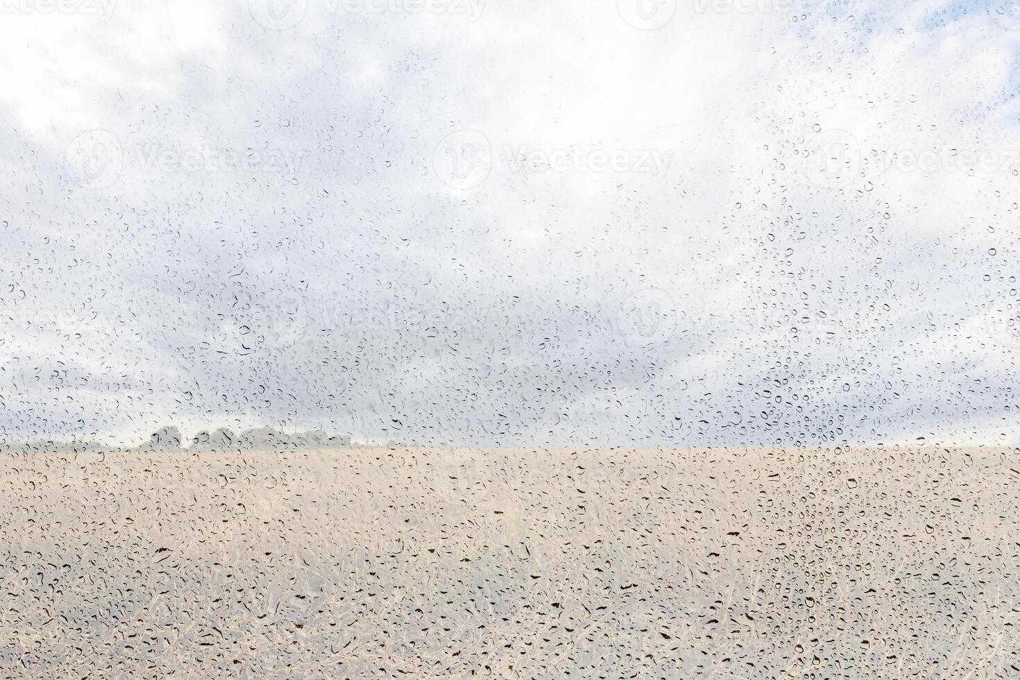 Agricultural field after rain with clouds in the sky behind wet glass in golden autumn. Bad weather concept. Abstract landscape. photo