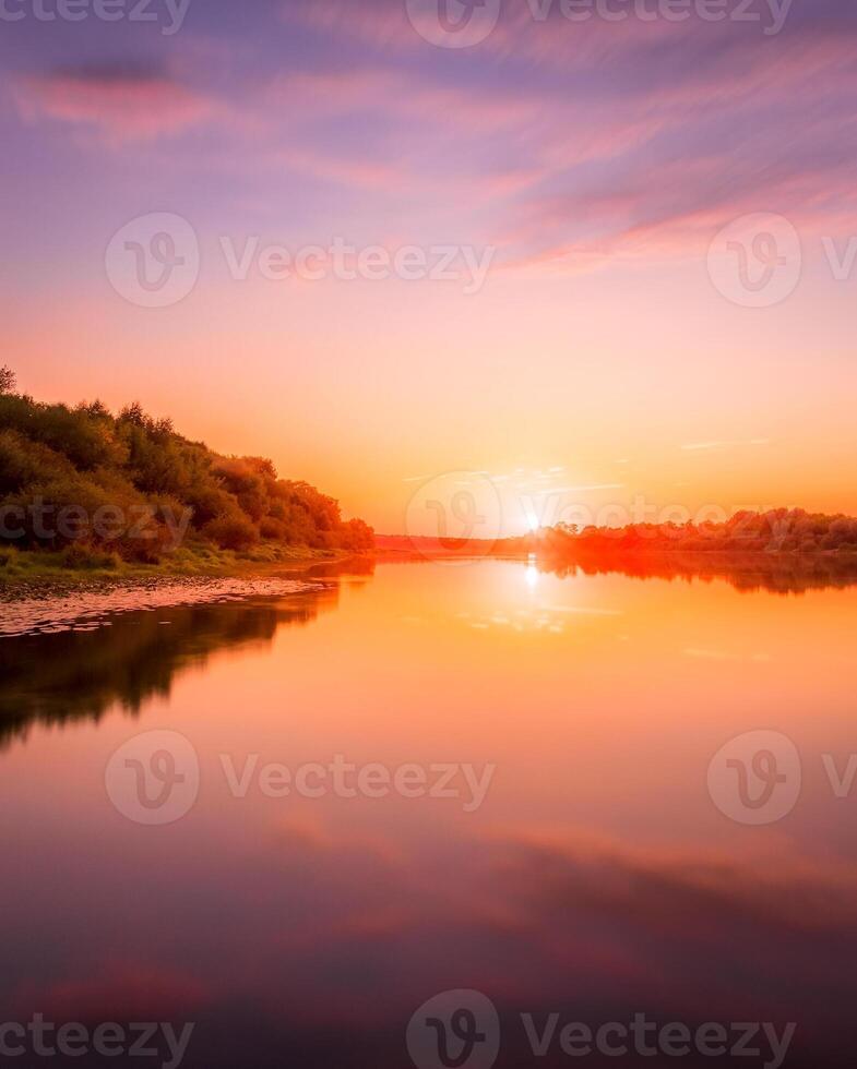 Sunset or dawn on a river with a cloudy sky and sun rays reflected in the water, water lilies and trees growing along the shore. photo