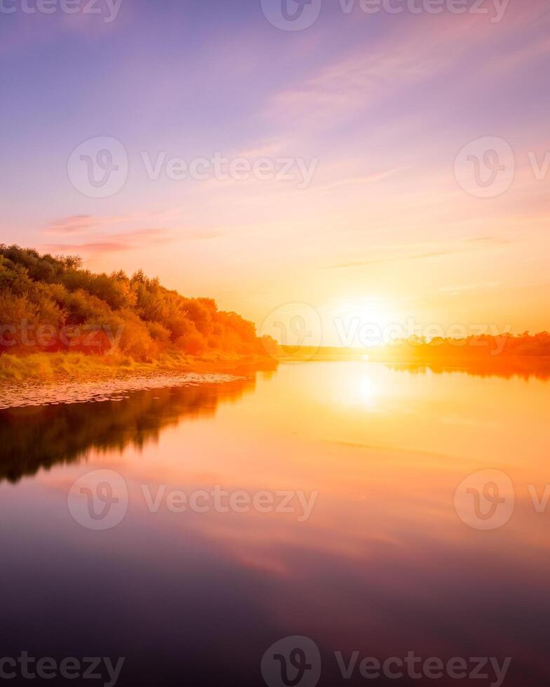 Sunset or dawn on a river with a cloudy sky and sun rays reflected in the water, water lilies and trees growing along the shore. photo