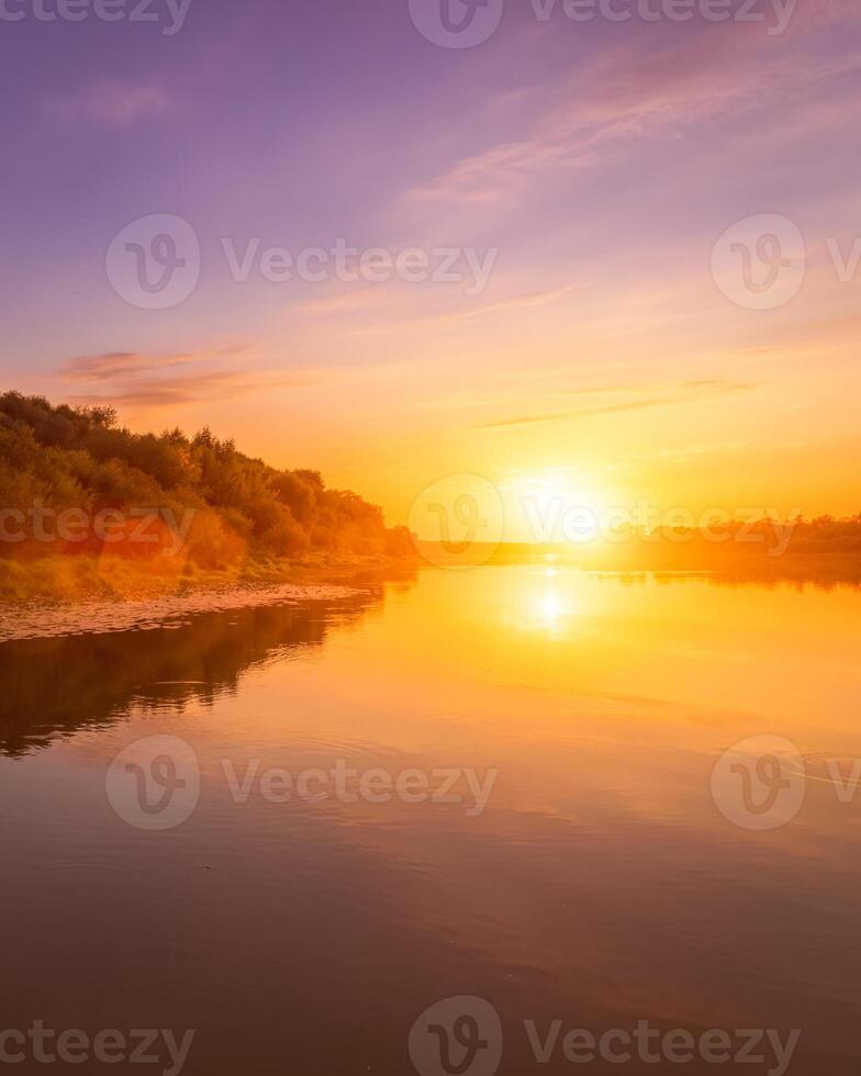 Sunset or dawn on a river with a cloudy sky and sun rays reflected in the water, water lilies and trees growing along the shore. photo