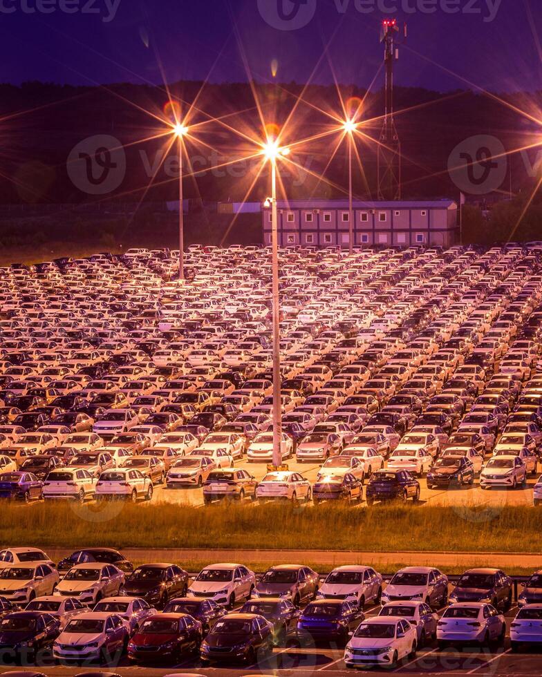 Volkswagen, Russia, Kaluga - AUGUST 26, 2020 New cars parked at distribution center automobile factory at night with lights. Parking on the open air. photo