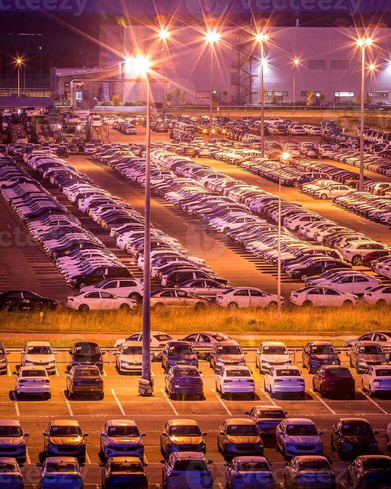 Volkswagen, Russia, Kaluga - AUGUST 26, 2020 New cars parked at distribution center automobile factory at night with lights. Parking on the open air. photo